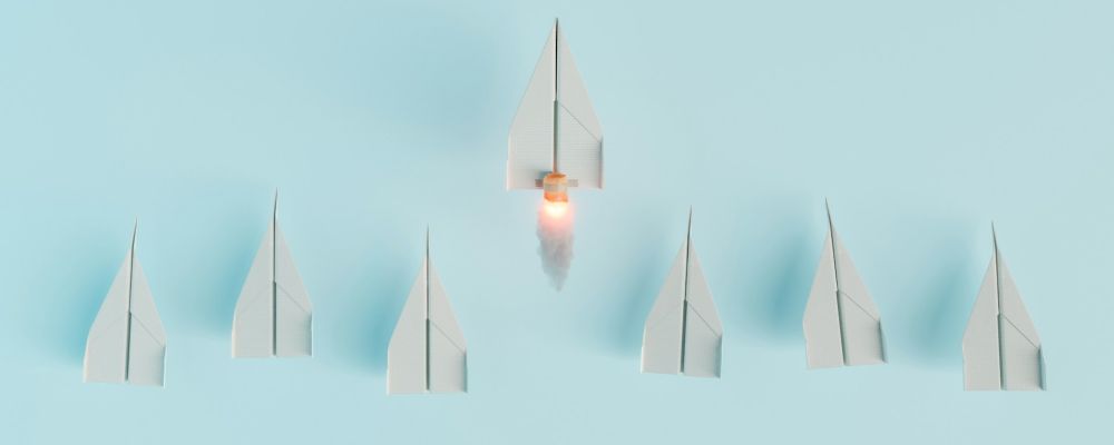 One lit paper plane leading a formation of others